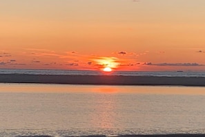 A sunset over a beach with calm water reflecting the sky. - Holiday home with 4 bedrooms (Norddeich)