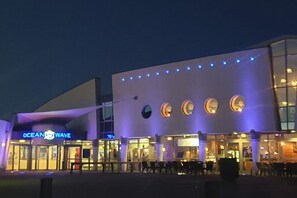 Een gebouw met een bord waarop 'OCEAN WAVE' staat en een reeks ronde ramen in de gevel.