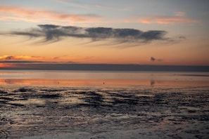 Een strand met een rustige zee en een zonsondergang.