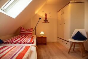 Een slaapkamer met een bed, een nachtkastje met een lamp, een kledingkast en een stoel.