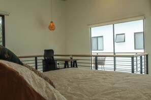 A bedroom with a large bed, a desk, and a balcony with a railing. - Howler Monkey Loft (Playas Del Coco)