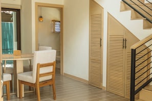 A room with a dining table and chairs, a staircase, and a door with louvered panels. - Tropical Hideaway Loft (Playas Del Coco)
