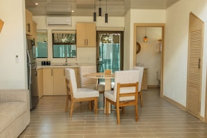 A modern kitchen with a dining area, wooden cabinets, and a built-in oven. - Tropical Hideaway Loft (Playas Del Coco)
