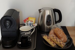 A kitchen setup with a coffee maker, a kettle, a coffee cup, a mug, a plate with bread, and a bag of Lipton tea. - Titilè: a new and comfortable room, surrounded by greenery, with a private entrance (ALGHERO)