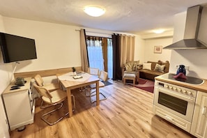 Un espacio habitable compacto con kitchenette, comedor y zona de estar.