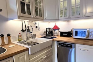 A modern kitchen with white cabinets, stainless steel appliances, and a wooden countertop. - Holiday apartment with 2 bedrooms (Bischofswiesen)
