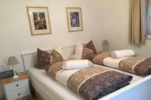 A double bed with patterned bedding, a bedside table with a lamp, and two framed pictures on the wall. - Holiday apartment with 2 bedrooms (Bischofswiesen)