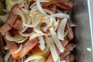 A close-up of sliced onions and ham in a metal container. - Sijixinghe Hotel (Dushanbe)