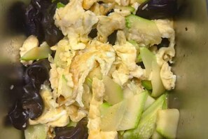 A close-up of a dish with scrambled eggs, green vegetables, and possibly black olives. - Sijixinghe Hotel (Dushanbe)