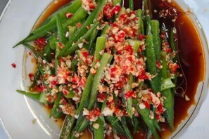 Un plat de légumes verts accompagné d’une sauce et d’ingrédients hachés.