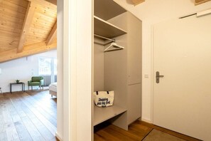 Ein Zimmer mit Holzboden, einer weißen Tür und einer an der Wand hängenden Kleideraufbewahrung.