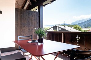 A red table with chairs on a balcony with a wooden fence and a view of mountains. - Holiday apartment with 2 bedrooms (Garmisch-Partenkirchen)