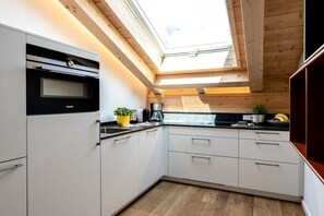 A modern kitchen with a skylight, white cabinets, and wooden flooring. - Holiday apartment with 2 bedrooms (Garmisch-Partenkirchen)
