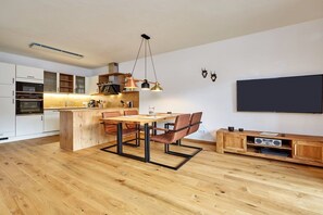 A modern kitchen with a central island, wooden cabinets, and a dining area with chairs. - Holiday apartment with 2 bedrooms (Garmisch-Partenkirchen)