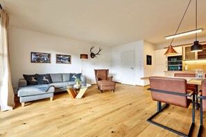 Ein modernes Wohnzimmer mit einer Couch, einem Couchtisch und einem Essbereich mit Stühlen.