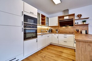 Eine moderne Küche mit weißen Schränken, einer Holz Arbeitsplatte und eingebauten Geräten.
