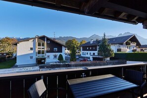 Ein Wohngebiet mit Häusern, einem Balkon und einer Bergkulisse im Hintergrund.