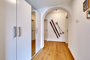Ein Flur mit Holzboden, weißen Wänden und einem Spiegelkleiderschrank.