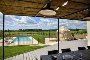 A pool area with a view of vineyards, a stone structure, and a dining table set for two. - Holiday home with 5 bedrooms (Bagnols sur Cèze)