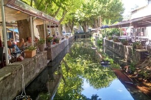 A canal-side café with outdoor seating, surrounded by trees and buildings. - Holiday home with 5 bedrooms (Bagnols sur Cèze)