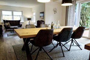 Een eetruimte met een houten tafel, zwarte stoelen en een kamerkleed met dessin.