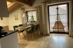 Een eetgedeelte met een houten tafel, stoelen en een raam met gordijnen.