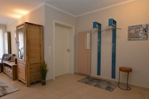 A hallway with a wooden cabinet, a door, a mirror, and a wall-mounted towel rack. - Holiday apartment with 2 bedrooms (Norddeich)