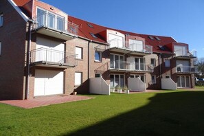 A multi-story residential building with balconies, a brick facade, and a red-tiled roof. - Holiday apartment with 2 bedrooms (Norddeich)