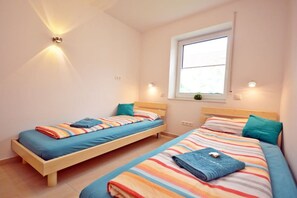 Een slaapkamer met twee eenpersoonsbedden, een raam en wandlampen.