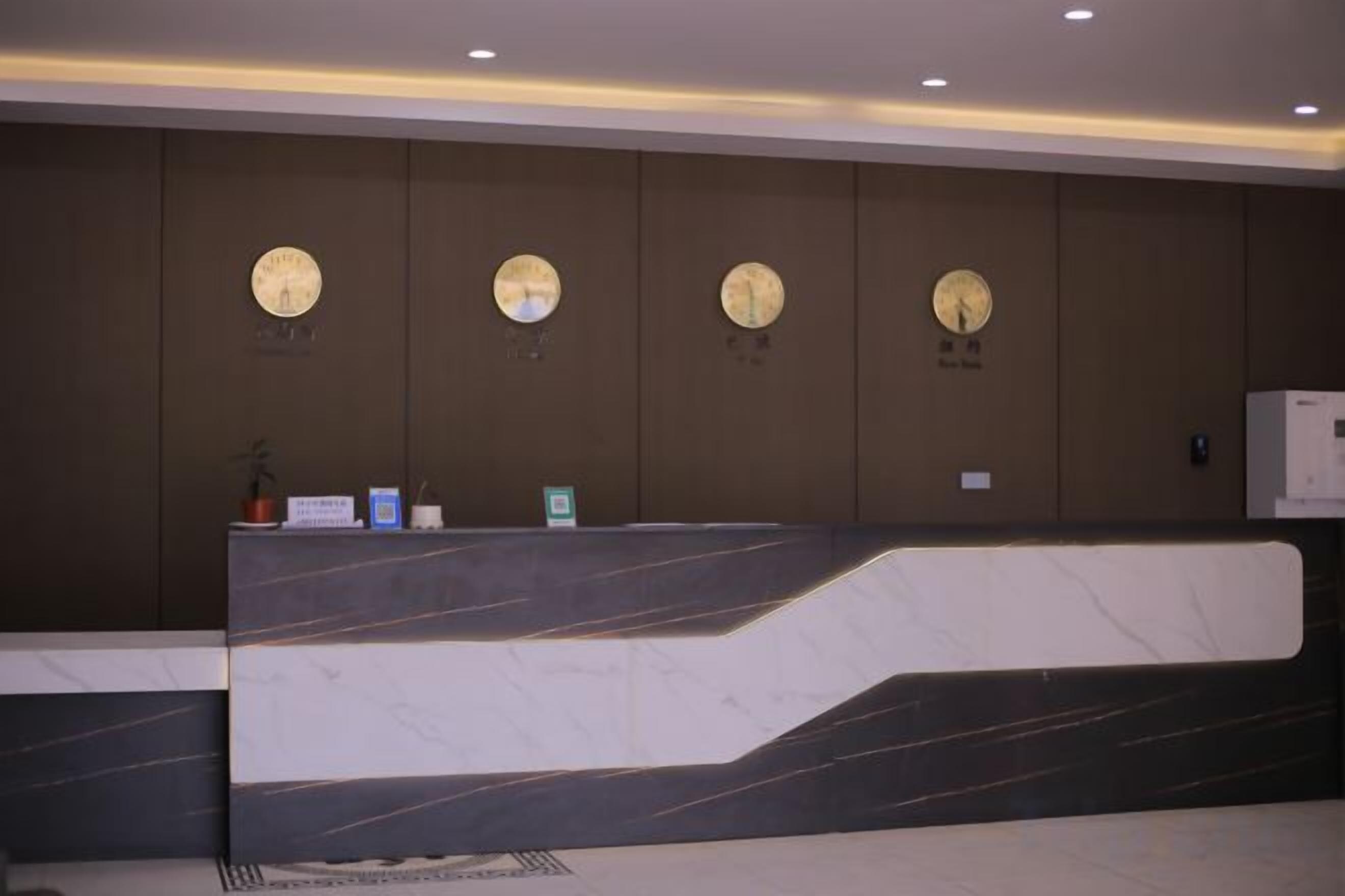 A reception desk with a marble top, clocks on the wall, and a small potted plant.