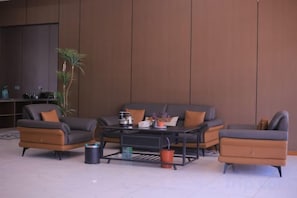 A modern living room with a sectional sofa, a coffee table, and a television. - Heyue Hotel (Dushanbe)