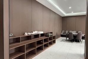 Un comedor moderno con una mesa larga y sillas, una estantería empotrada con diversos objetos, y piso de baldosas.