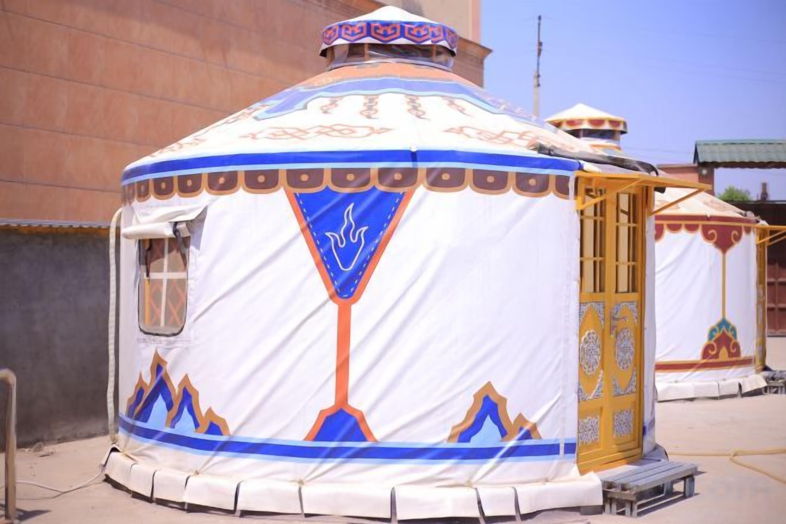 A traditional yurt with a door, a window, and a decorative top.