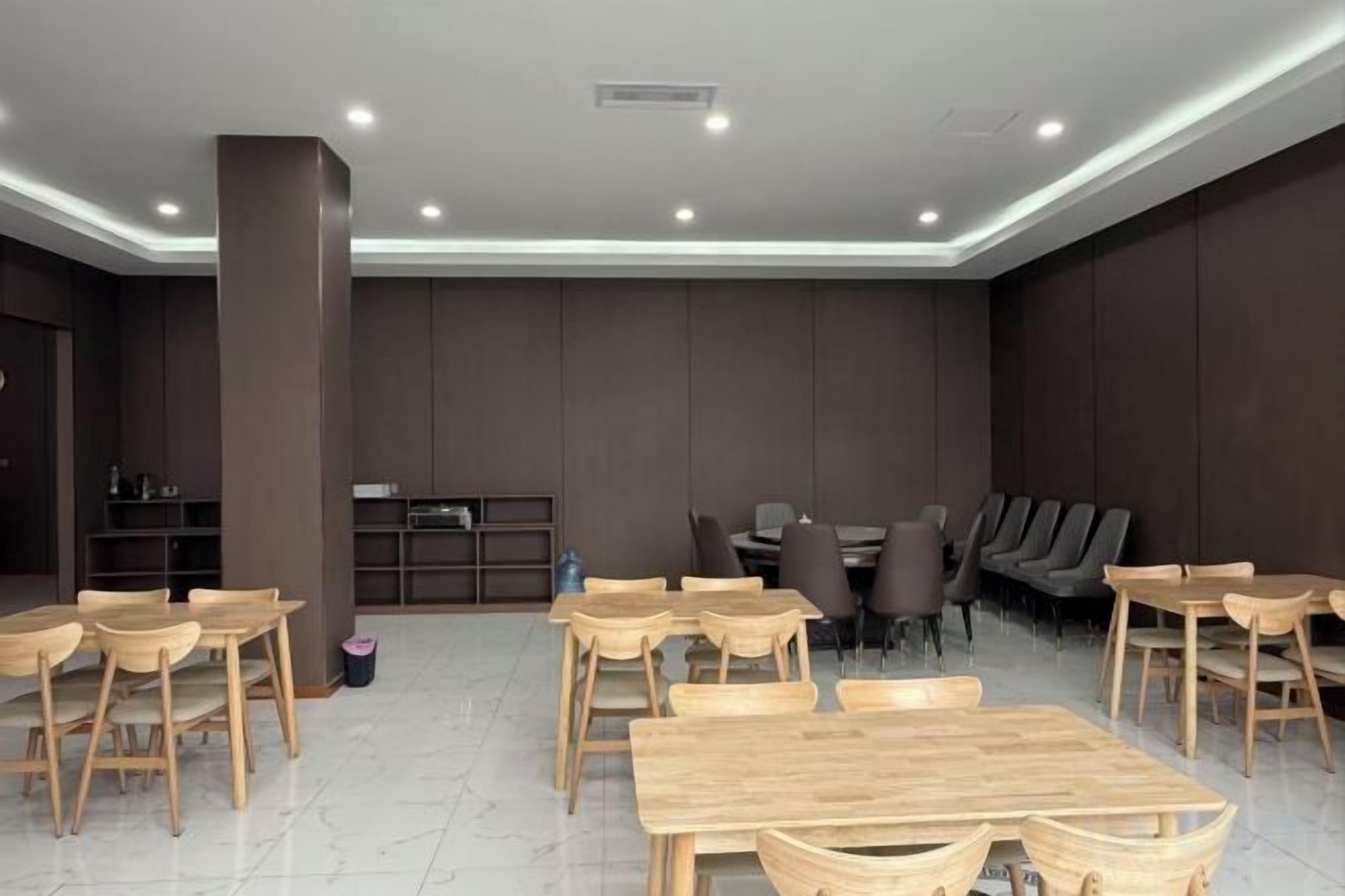 A modern dining area with wooden tables and chairs, a bar area, and a seating section with sofas and chairs.