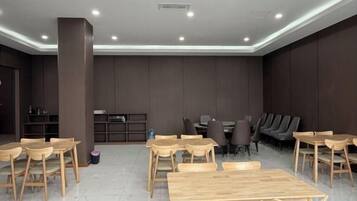 A modern dining area with wooden tables and chairs, a bar area, and a seating section with sofas and chairs.