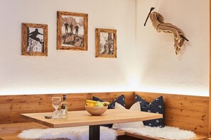 A cozy seating area with a wooden table, a bowl of fruit, and a bottle of liquor. - Holiday apartment no. 3 - Guesthouse zum Wurm (Reit im Winkl)