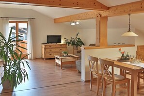 Un intérieur en bois comprenant un coin repas, un téléviseur et une plante en pot.