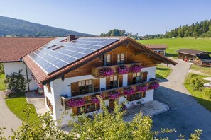 Ein zweistöckiges Gebäude mit einem geneigten Dach, Solaranlagen und einem Balkon mit Blumenkästen.