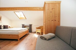 Ein Schlafzimmer mit einem hölzernen Bett, einem Sofa, einem Schreibtisch und einem Oberlicht.