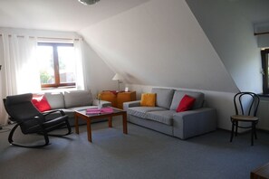 Ein Wohnzimmer mit einer Couch, einem Sessel, einem Tisch und einer Lampe.