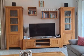 Un salon équipé d’un téléviseur à écran plat, de meubles en bois et d’une bibliothèque.
