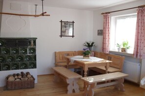 Ein Essbereich mit einem Holztisch und Bänken, einem an der Wand befestigten Heizkörper und einem Fenster mit Vorhängen.