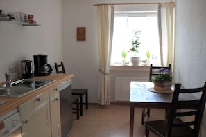 A compact kitchen with a sink, stove, and a window with curtains. - Holiday apartment with 2 bedrooms (Garmisch-Partenkirchen)