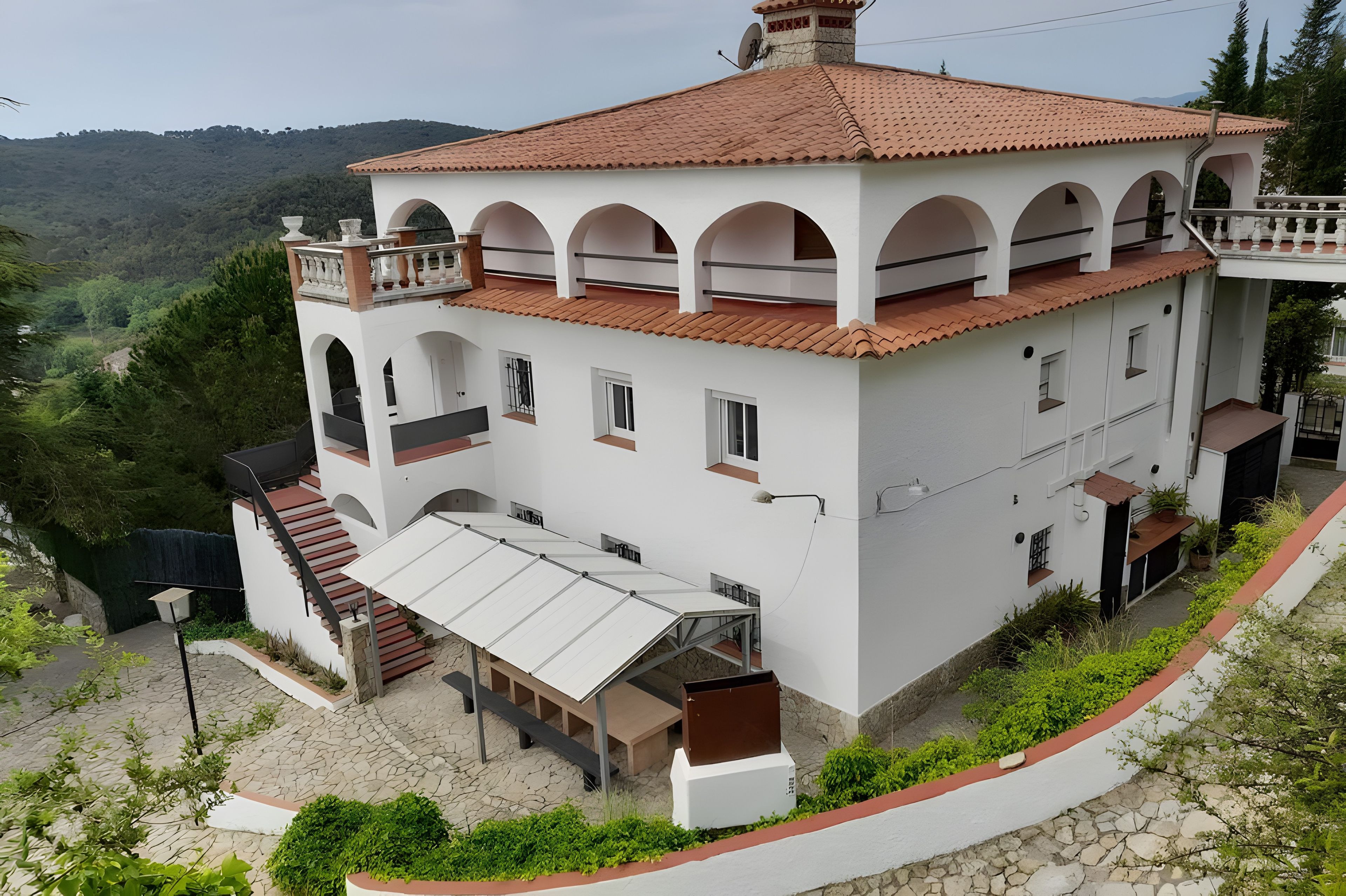 A two-story building with a red-tiled roof, white walls, and multiple balconies.