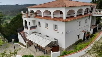 A two-story building with a red-tiled roof, white walls, and multiple balconies.