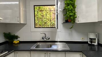 A kitchen with a stainless steel sink, a window with a view of greenery, and a coffee maker on the counter.