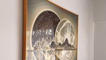 Ein gerahmtes Kunstwerk mit abstrakten Designs und reflektierenden Oberflächen an einer Wand.