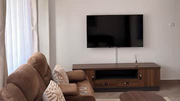 Ein modernes Wohnzimmer mit einem braunen Sofa, einem Flachbildfernseher und einem Holztisch.