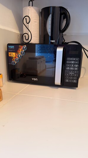 Een magnetron met een digitaal display, bedieningspaneel en een logo van het merk.