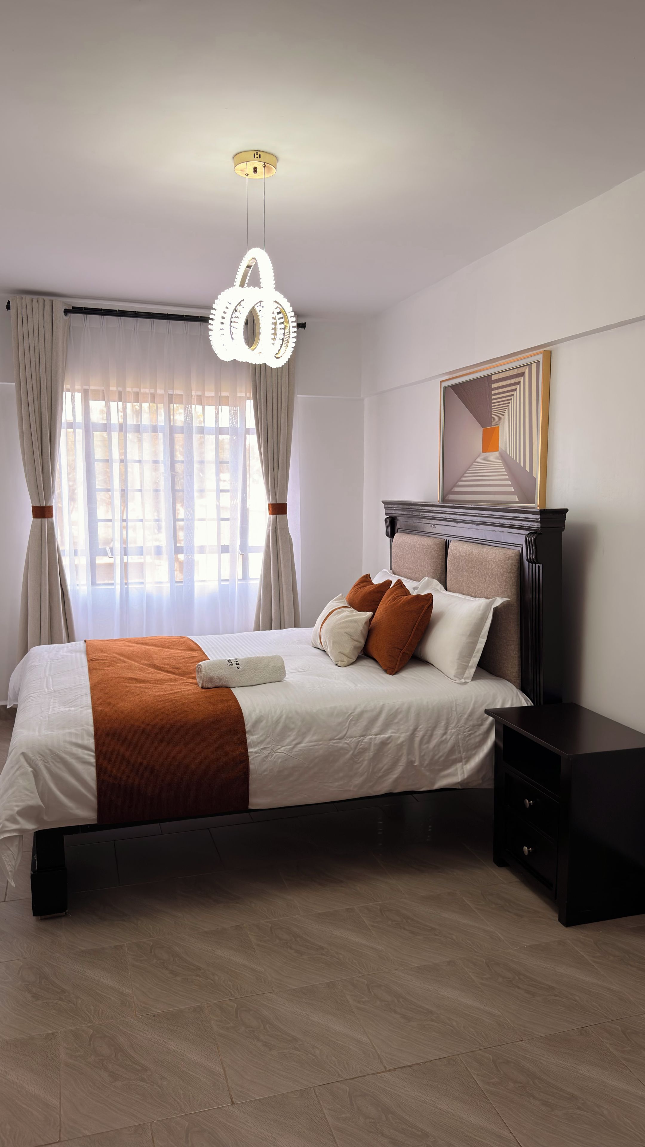 Ein Hotelzimmer mit einem Bett, einem Nachttisch und einem großen Fenster mit Vorhängen.